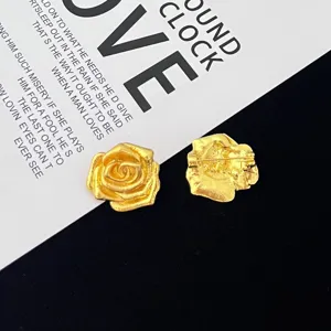 Vintage gold rose flower brooch detailed view showing textured petals and back pin mechanism.