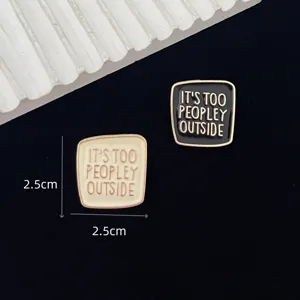 Close-up detail of square enamel pin brooch with funny letter print, alloy fashion accessory.
