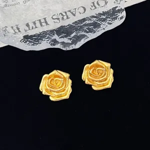 Close-up detail of the vintage gold rose flower brooch accessory with exquisite metallic texture.