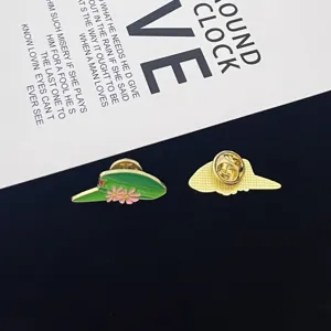 Detailed shot of metal enamel pin featuring leaf and pink flower design, showing front and back.