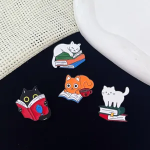 Close-up details of the cute cat reading metal brooches, showing fine enamel craft.