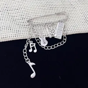 Music theme brooch detail, silver tone safety pin with guitar and notes charms design.