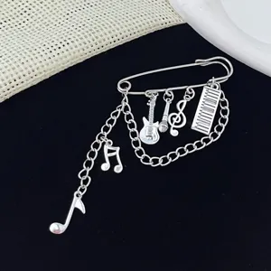Close-up of vintage music themed brooch detail showing guitar charm safety pin accessories