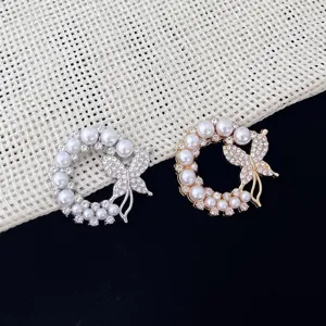 Exquisite pearl butterfly brooch detail, shiny crystal wreath design for elegant coat accessories.
