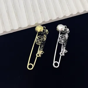 Gedetailleerde close-up van gotische punk skelet veiligheidsspelden in goud en zilver.