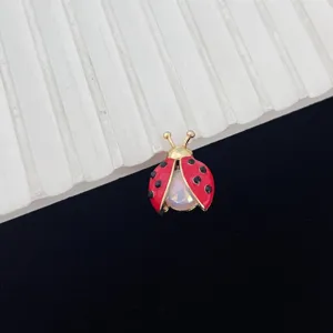 Chique emaillen lieveheersbeestje broche met iriserende steen, elegante gouden accessoire.