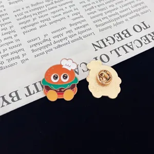 Close up detail of cute cartoon burger enamel pin showing front and secure back clasp.