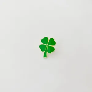 Green enamel four-leaf clover brooch with gold trim, stylish and trendy fashion accessory detail.