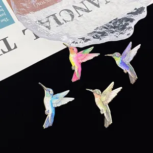 Detailed shot of colorful hummingbird enamel brooch pins, featuring fine metal craft and cute design.
