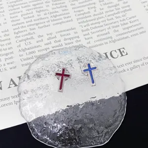 Close-up detail of cross enamel metal brooch pin, showing vibrant red and blue color finish.
