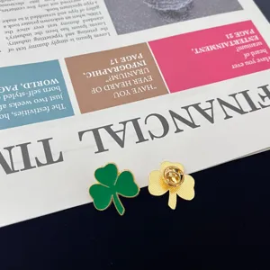 Close-up detail shot of clover enamel pin, featuring green front and gold back structure.