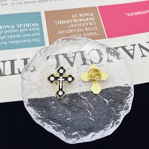 Detailed view of metal cross brooch with black enamel and white flower design pin.