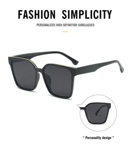 Close-up detail shot of trendy large-frame sunglasses with golden top rim and black lenses.