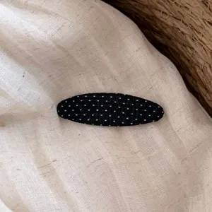 Dettaglio molletta per capelli in tessuto a pois, design minimalista dolce per frangia.