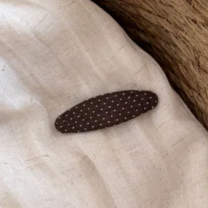 Dettaglio molletta per capelli in tessuto a pois marroni, consistenza morbida e carina.