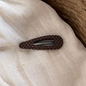 Dettaglio molletta per capelli in tessuto a pois marrone, fermaglio goccia per acconciature.