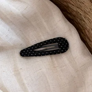 Dettaglio molletta per capelli a goccia nera a pois, clip carina in tessuto per look.