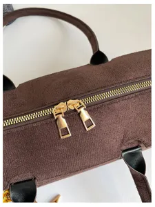 Nahaufnahme der braunen Veloursleder Zylinder Handtasche mit goldenen Reißverschlüssen.