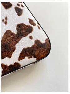 Vista dettagliata della borsa a spalla retrò con stampa vacca, texture premium e bordi.