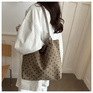 Vista dettagliata della borsa in tela con pois neri chic, tracolla elegante per stile casual.