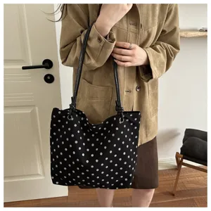 Primo piano di una borsa tote in tela a pois con manici neri in stile casual elegante.