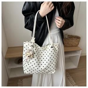 Vista dettagliata della borsa tote in tela a pois bianchi con ciondolo a forma di orsetto.