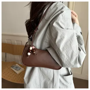 Brown leather underarm shoulder bag with beaded charm detail showing style and texture close-up.