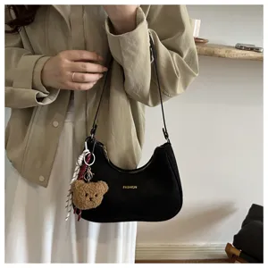 Borsa a spalla nera alla moda a forma di mezzaluna con ciondolo a orsetto per donne chic.
