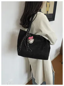 Detailansicht der schwarzen Tasche mit dem süßen Plüschbären Anhänger und dem Schleifenriemen.