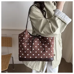 Vista dettagliata della borsa tote marrone a pois con fiocco, texture scamosciata e dettagli.