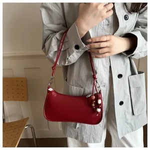 Red leather shoulder bag with beaded charm, elegant underarm bag detail for stylish daily wear.