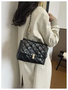 Dettaglio borsa a tracolla trapuntata lucida, catena elegante e chiusura chic quotidiana.