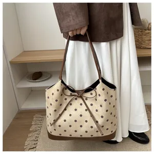 Primo piano di una graziosa borsa a pois con dettaglio fiocco e manici marroni.