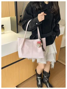 Detailansicht der minimalistischen rosa Tasche mit Bärenanhänger und Schulterriemen für Alltag.