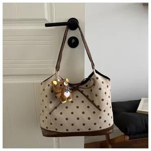 Dettaglio borsa tote a pois con grazioso fiocco e affascinante ciondolo peluche orsetto.