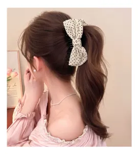 Vista detallada de una encantadora pinza para el cabello de tela con corazones y un lindo lazo.