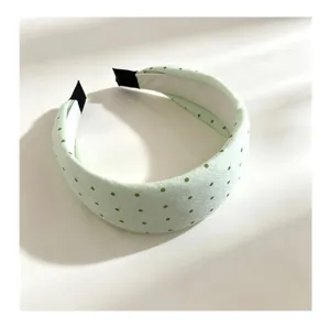 Detalle de diadema de tela verde pastel con lunares, accesorio de pelo estilo dulce.