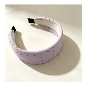 Primer plano detallado de una diadema morada pastel con lunares y diseño elevado.