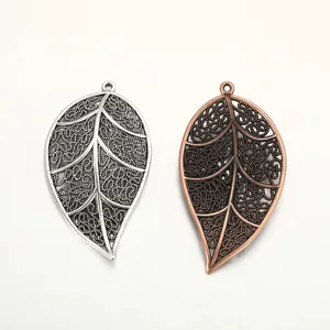 Close-up detail of vintage hollow leaf alloy jewelry pendant charms, silver and bronze finish.