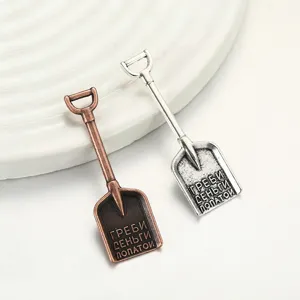Mini shovel metal charm detail, alloy DIY jewelry pendant, bronze and silver finish close-up view.