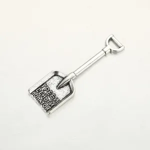 Close-up detail of a silver-toned metal shovel charm, featuring engraved text design.