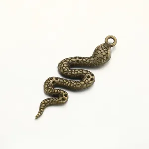 Close-up of retro bronze snake pendant detail, showing textured scales and hanging ring.