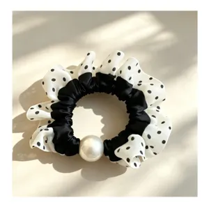 Primer plano detallado del coletero de lunares blancos y negros con gran decoración de perlas.