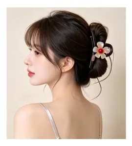 Primer plano de una elegante pinza para el cabello con diseño floral iridiscente y detalle rojo.
