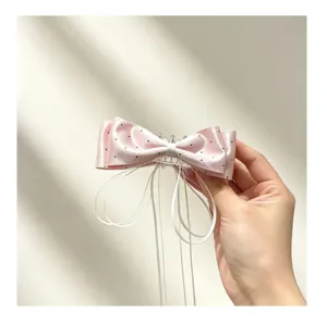 Roze stippen satijn strik haarklem met stijlvol wit lint voor dagelijkse haarstyling.