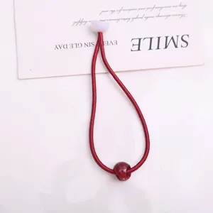 Elastico per capelli rosso con perlina rossa e fibbia in plastica bianca per uso quotidiano.