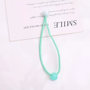 Vista dettagliata di un grazioso elastico per capelli verde con perla, ideale per bambini.