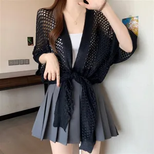 Detail shot of a black hollow knit cardigan showcasing the breathable mesh texture and styling.