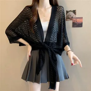 Detail shot of a black hollow-out knitted summer cardigan, stylish cape shawl top.