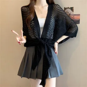 Close-up detail of a women's black hollow knit open front cardigan cape showcasing style.